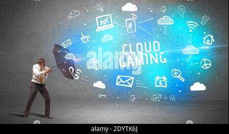 Businessman defending with umbrella from CLOUD GAMING inscription, modern technology concept Stock Photo