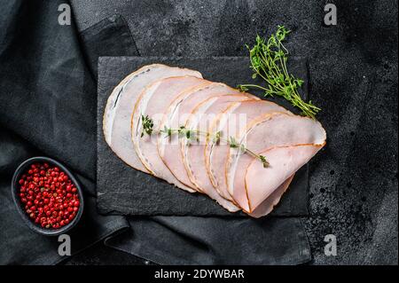Slices of pork ham with thyme. Organic meat. Black background. Top view. Stock Photo