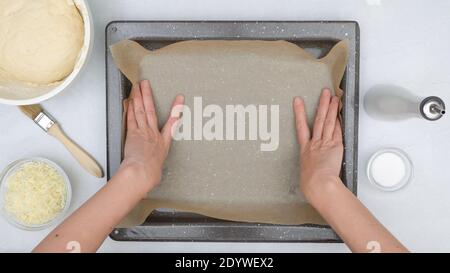 Chef lines baking pan with parchment paper. Cheese bread step by step recipe. Baking process, close up view from above Stock Photo