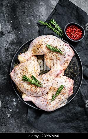 Raw chicken drumsticks with thighs, fresh herbs, cooking. Black background. Top view Stock Photo