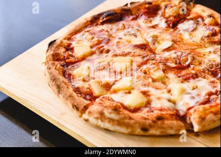Tasty tradition Hawaiian and Salami pizza pie cooking ingredients bacon tomatoes on black table in original restaurant background. Top view of hot pep Stock Photo