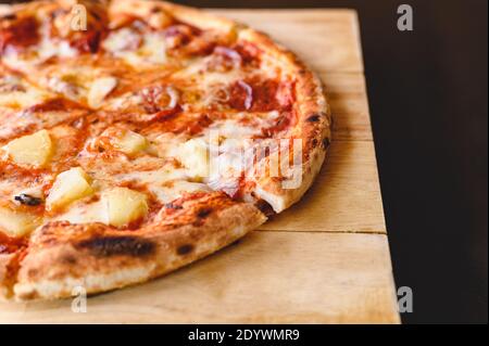 Tasty tradition Hawaiian and Salami pizza pie cooking ingredients bacon tomatoes on black table in original restaurant background. Top view of hot pep Stock Photo