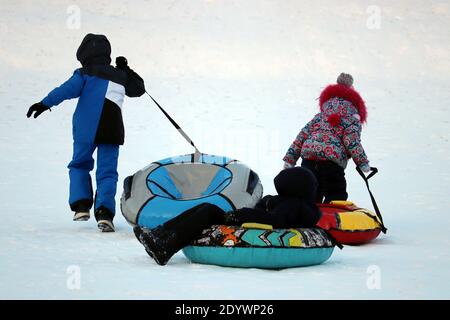 Children having fun on snow tubes. Kids is riding a tubing, winter entertainment Stock Photo