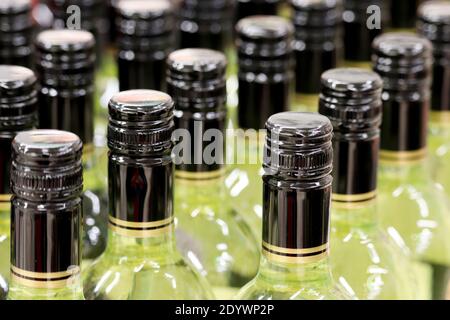 Wine bottles in a row, selective focus. Liquor store, white wine production concept Stock Photo