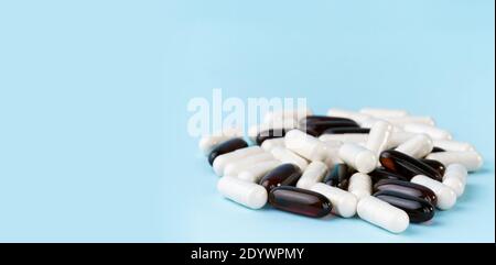 Pharmaceutical pills and vitamins. Medicine or supplement capsules on blue surface. Probiotic, inulin, glucosamine pile. Stock Photo