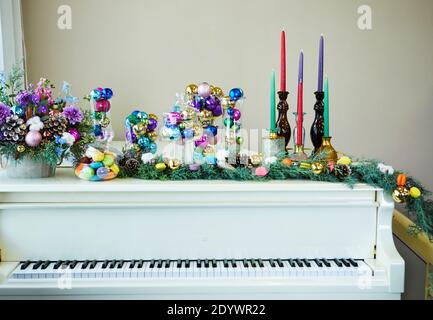 White piano decorated in New Year's style, Christmas tree, Christmas toys and balls, candles and macarons. New Year concept Stock Photo