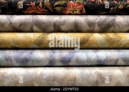 Rolled up rolls of vinyl wallpaper. Different textures and colors, as background. Wallpapers with abstract patterns for the wall. Decorative materials Stock Photo