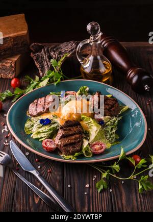 Eggs benedict with beef meat on a large white plate.. Traditional english breakfast with eggs Benedict, cherry tomato, lettuce. Benedict egg served on Stock Photo