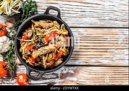 Udon stir fry noodles with chicken and vegetables in a pan. White background. Top view. Copy space Stock Photo