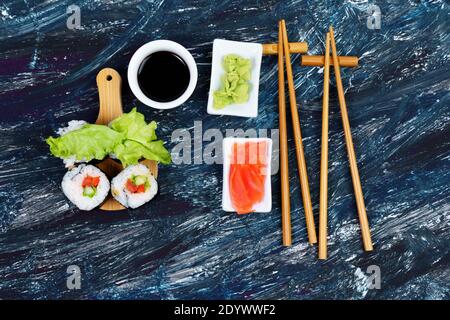 Vegan sushi rolls with avocado, cucumber salad and tomato black background. Healthy vegan food concept.