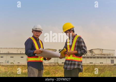 Construction Engineer two people hold blueprint working on site estate building construction Stock Photo