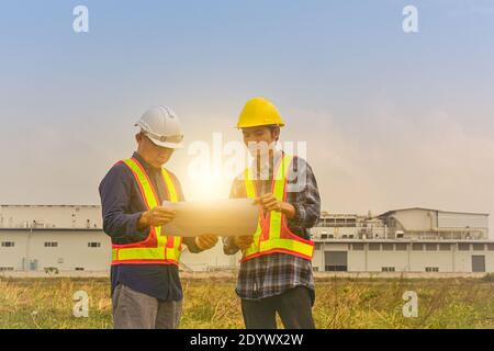 Construction Engineer two people hold blueprint working on site estate building construction Stock Photo
