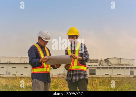 Construction Engineer two people hold blueprint working on site estate building construction Stock Photo