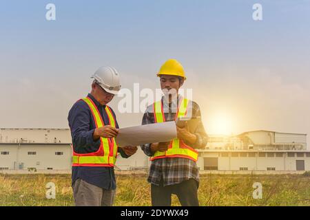 Construction Engineer two people hold blueprint working on site estate building construction Stock Photo