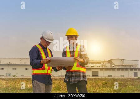 Construction Engineer two people hold blueprint working on site estate building construction Stock Photo