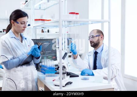Young scientist analysing and doing experiments chemistry lab. Team of chemical chemists working together in sterile microbiology lab doing research. Stock Photo
