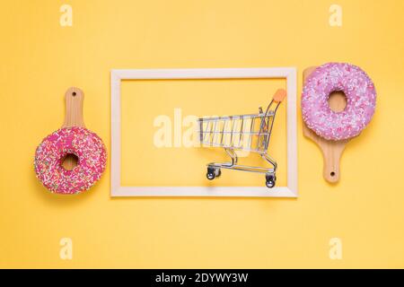 two Donuts with pink sugar glaze and sprinkled with colorful pastry crumbs, on a yellow background. the concept of shopping Stock Photo