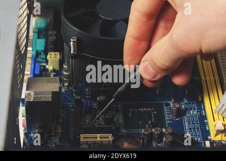 Close-up on the hands with screwdriver tool of the technician repairing a PC computer. Stock Photo
