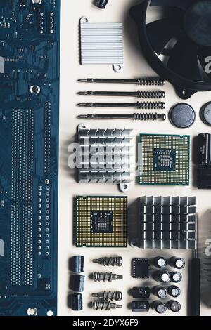 Top view of computer parts with CPU, fan cooler, battery, capacitors, radiator, chip, screwdrivers on white table background with copy space. DIY constructor concept. Stock Photo