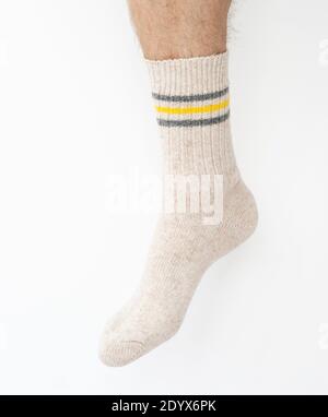 Beige woolen sock on a man's leg on a light background Stock Photo