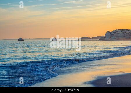 Landscape of beautiful sandy beach Praia da Rocha with rocks and cliffs in Portimao town of Algarve district, golden sunset over waves of Atlantic Oce Stock Photo