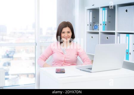 Smiling business woman sitting in beautiful office Stock Photo