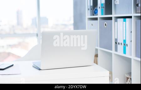 Modern laptop on white table in light office Stock Photo