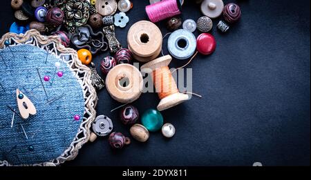 Top view of retro threads and aged buttons on dark background Stock Photo