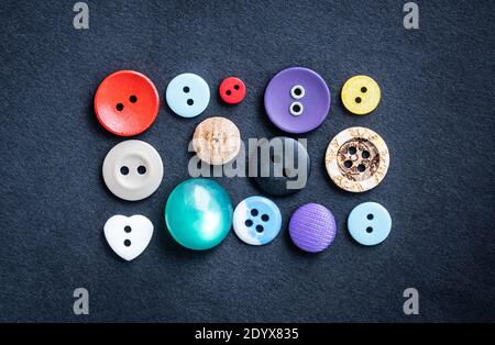 Close up view of different sewing buttons lying on dark cloth Stock Photo