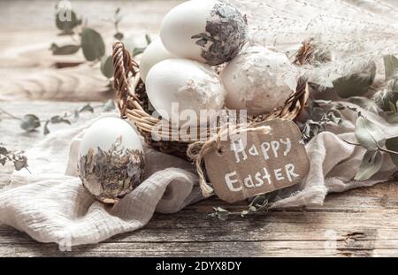 Beautiful Easter eggs in a basket decorated with dried flowers. Happy Easter concept. Stock Photo