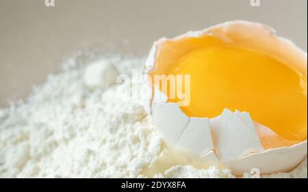 Cracked chicken egg with yolk on white flour Stock Photo