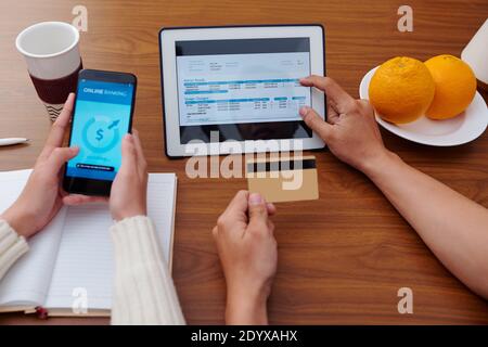 Hands of couple checking electric energy consumption on tablet computer and paying bill via banking application Stock Photo