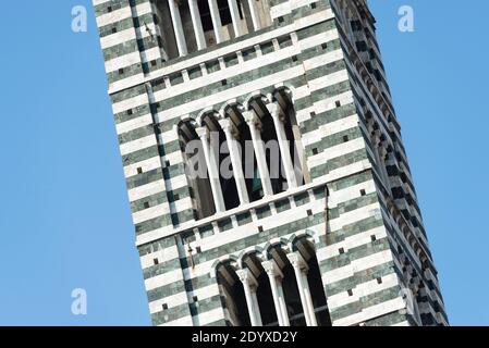 Part of the facade of Siena Cathedral clock tower in the sunlight against blue sky, Tuscany, Italy Stock Photo