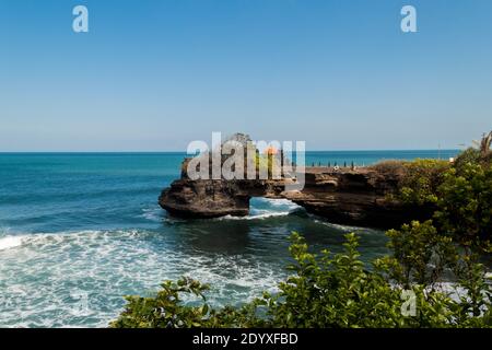 Batu Bolong Temple on the natural bridge near Tanah Lot Temple on a sunny summer day Stock Photo