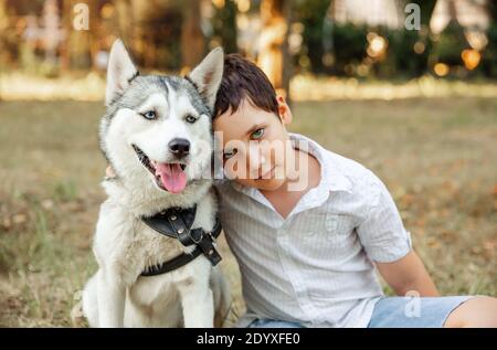 Selective focus on husky dog. Blurred happy kid cuddling puppy Stock Photo