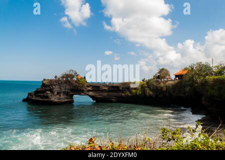 Batu Bolong Temple and the natural bridge in the sea at Tanah Lot Temple Stock Photo