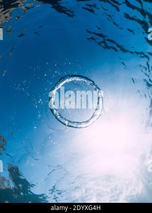 Ring bubble underwater and sun in blue ocean. Water texture. Stock Photo
