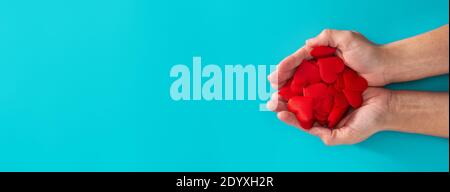Woman hands holding red hearts on blue background Stock Photo