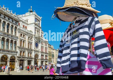 View of souvenir clothing and Torre dell'Orologio in St Mark's Square, Venice, Veneto, Italy, Europe Stock Photo