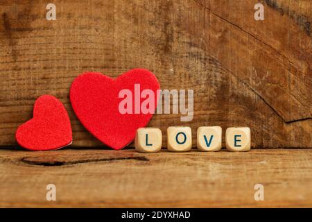 Two red paper hearts on a wooden background with a love sign Stock Photo