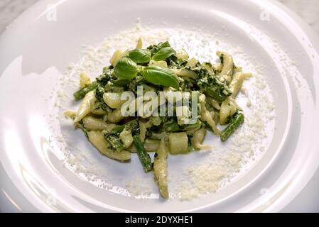 Trofie al pesto - Italian pasta with basil pesto sauce, potatoes and green beans  typical of Genoa, Liguria, Italy - close up in white dish with grate Stock Photo