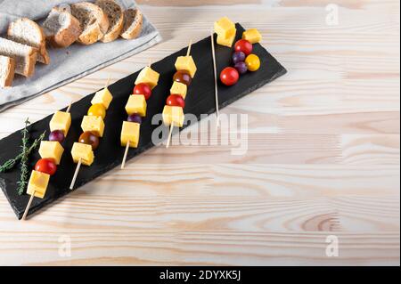 canapes from olives, cheese and cherry tomato on skewers. finger food. slices of cheese and tomatoes on a skewer. canapes with cheese, grapes, olives