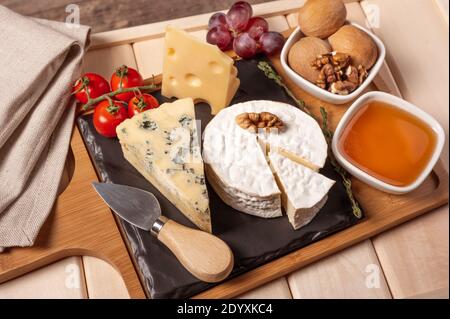 wooden tray for breakfast with brie cheese, honey, walnuts, tomato. cheese dessert on the wooden tray with black plate Stock Photo