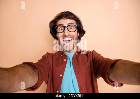 Photo portrait of excited guy taking selfie isolated on pastel beige colored background Stock Photo