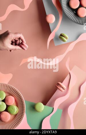 Levitation and balance composition with flying macaroons. Abstract shapes and lines. Natural sunlight. Layered paper background in salmon pink and