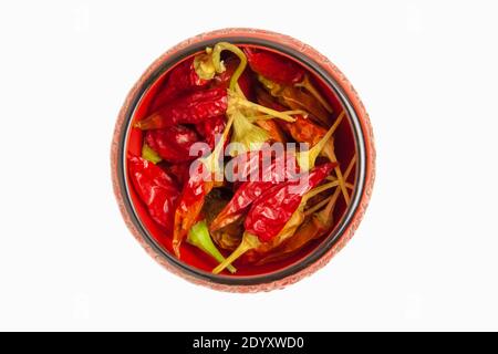 Dry red hot pepper in a red ceramic bowl, isolated on a white background. The view from the top Stock Photo
