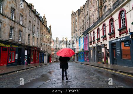 Woman holding red umbrella in rain in Victoria Street in Old Town of Edinburgh, Scotland, UK Stock Photo