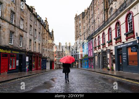 Woman holding red umbrella in rain in Victoria Street in Old Town of Edinburgh, Scotland, UK Stock Photo