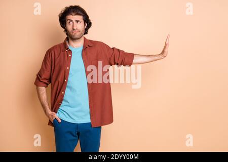 Portrait of attractive tired skeptic guy showing palm aside refusal isolated over beige pastel color background Stock Photo