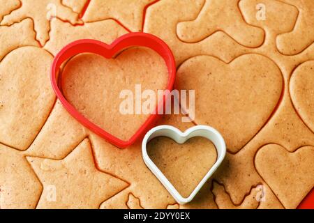 Dough for making heart shaped cookies on Valentines Day. Homemade pastry. Red and green plastic baking molds. Stock Photo